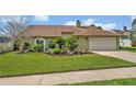 Well-maintained single-story home with green lawn, mature trees, and beautiful landscaping at 1002 Ohanlon Ct, Oviedo, FL 32765