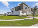 Contemporary townhome features manicured lawns, a two-car garage, and neutral two-tone exterior paint at 1195 Boardwalk Pl, Kissimmee, FL 34747
