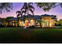 Beautiful twilight shot of one-story home with lights on showing lush green lawn, two large palm trees at 2008 Water Key Dr, Windermere, FL 34786
