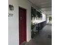 Hallway view of unit #2597 entrance with red door, walkway, and tropical landscaping at 2597 Oak Park Way # 205, Orlando, FL 32822