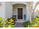 Inviting front porch with decorative chairs, a wreath on the door, and lush landscaping at 2817 Noble Crow Dr, Kissimmee, FL 34744