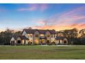 A view of the home and its expansive front lawn, framed by a picturesque sunset at 5500 State Road 33, Clermont, FL 34714