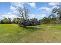 Cozy single-Gathering home with a wooden porch, complemented by a spacious green yard and mature trees at 7322 Groveland Farms Rd, Groveland, FL 34736