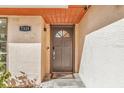 Close-up of a modern front door with a decorative window, stylish hardware, and a welcome mat on a stone tile porch at 7325 Burnway Dr, Orlando, FL 32819