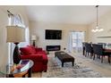Sunlit living room features a red sofa, electric fireplace, and adjacent dining area with modern chandelier at 877 Scrub Jay Way, Davenport, FL 33896