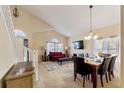 Open living and dining area with vaulted ceiling, large windows, and staircase with white railing at 877 Scrub Jay Way, Davenport, FL 33896