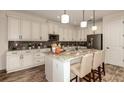 Modern kitchen featuring white cabinets, granite countertops, stainless steel appliances, and island seating at 145 Old Moss Cir, Deland, FL 32724