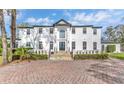 Exterior view of grand white home with black roof, stone walkway, and manicured landscaping at 1943 Wingfield Dr, Longwood, FL 32779