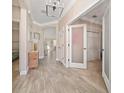 Inviting hallway featuring wood-look tile flooring, elegant lighting fixtures, and access to bedrooms at 4590 Sw 99Th St, Ocala, FL 34476