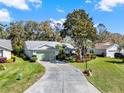 Inviting single Gathering home showcasing manicured lawn and concrete driveway leading to an attached two-car garage at 4721 Tara View Road, Leesburg, FL 34748