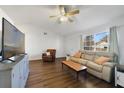 Cozy living room with hardwood floors, a large window, a comfortable leather sofa, and a modern entertainment center at 5317 Montford Pl, Apopka, FL 32712