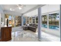 Enclosed sunroom featuring a comfortable gray couch, tiled floors, and a view of the backyard swimming pool at 5317 Montford Pl, Apopka, FL 32712