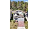 Aerial view of a gray two-story home with brick driveway, complemented by lush green trees at 869 Rivers Crossing St, Clermont, FL 34714