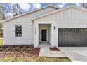 Close up of a house showing siding, black door and garage, and new landscaping at 12380 Sw 71St Lane Rd, Ocala, FL 34481