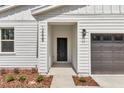 This is a close up of the home's entryway with a black door, modern lighting, and manicured landscaping at 12639 Sw 78Th Pl, Dunnellon, FL 34432