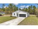 Attractive one-story home with a white exterior, two-car garage, and pristine lawn at 12639 Sw 78Th Pl, Dunnellon, FL 34432