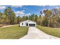 Beautiful white home with a long driveway leading to an attached two-car garage and lush green lawn at 12639 Sw 78Th Pl, Dunnellon, FL 34432