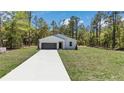 New home with a bright white exterior, lush green lawn, and a long concrete driveway at 13274 Sw 82Nd Ln, Dunnellon, FL 34432