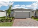 Exterior view of a one-story home with a two-car garage, brick driveway, and landscaping at 3876 Giorgio Dr, Winter Haven, FL 33884