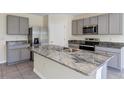 Modern kitchen island with granite countertops, stainless steel appliances, and gray cabinetry at 39 Hickory Course Way, Ocala, FL 34472