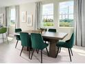 Bright dining room with large windows, a wooden dining table and six green velvet chairs at 4969 Kaia Ave, Winter Haven, FL 33884
