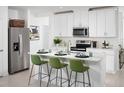 Modern kitchen features white cabinets, stainless steel appliances, and a center island with seating for three at 4969 Kaia Ave, Winter Haven, FL 33884