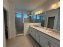 Elegant bathroom with double vanity, quartz countertops, white cabinets and a glass-enclosed shower at 5221 Kildare Pl, St Cloud, FL 34771