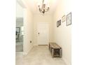 Welcoming foyer with neutral tile flooring, a bench, decorative art, and a view into an office space at 701 Bonsai St, Apopka, FL 32703