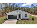 Modern one-story home featuring a gray garage door, a well-maintained lawn, and tasteful landscaping at 7117 Sw 131St Ave, Ocala, FL 34481