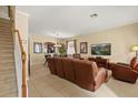Bright living room showcasing tile floors, comfortable leather seating, staircase, and a media center at 2508 Archfeld Blvd, Kissimmee, FL 34747