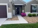 Charming home entrance with a dark front door, stone landscaping, and tidy green grass at 6832 Sw 93Rd Ave, Ocala, FL 34481