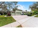 Side view of a green home featuring a three car garage and brick paved driveway at 701 Palenci Ct, Winter Springs, FL 32708