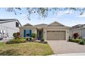 Inviting home with a paver driveway, lush landscaping, and charming blue shutters at 7977 Hanson Bay Pl, Kissimmee, FL 34747