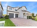 Beautiful two-story home featuring a brick paver driveway, two-car garage, and manicured lawn at 9947 Summerlake Groves St, Winter Garden, FL 34787