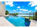 Beautiful pool overlooking a serene lake, surrounded by lush landscaping and a black fence at 15469 Shorebird Ln, Winter Garden, FL 34787