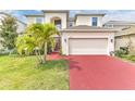 Charming two-story home featuring a manicured lawn, vibrant landscaping, and a red brick driveway leading to an attached garage at 2246 Rush Bay Way, Orlando, FL 32824