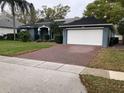 Charming blue single-story home with a brick driveway, well-manicured lawn and trimmed shrubs at 4024 Lillian Hall Ln, Orlando, FL 32812