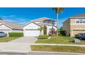 Beautifully landscaped home featuring lush green grass, decorative plantings, and a brick paved driveway at 5239 Los Palma Vista Dr, Orlando, FL 32837