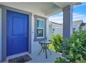 Inviting front porch featuring a vibrant blue door, cozy seating, and lush green foliage at 659 Daring Dr, Davenport, FL 33837