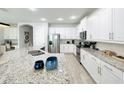 Bright kitchen featuring white cabinetry, stainless steel appliances, granite countertops and an island with bar stool seating at 7717 Graben St, Kissimmee, FL 34747