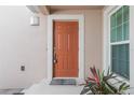 Close up of a wood front door with a welcome mat and neutral stucco siding at 1244 Romani Ave # 1244, Davenport, FL 33896