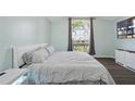 Bright bedroom with a large window, soft blue walls, and elegant dark wood floors at 215 Elderberry Dr, Davenport, FL 33897