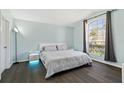 Serene bedroom with a large window, soft blue walls, and elegant dark wood floors at 215 Elderberry Dr, Davenport, FL 33897