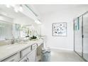 Bright bathroom featuring double sinks, decorative art, and a glass-enclosed shower with modern fixtures at 2305 Sirena Ln, Mount Dora, FL 32757