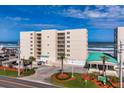 Condominium building exterior featuring a large green awning, beach access and palm trees at 4495 S Atlantic Ave # 5020, Ponce Inlet, FL 32127