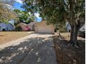 View of a single-story home, including front yard, driveway, and some mature trees at 8040 Equitation Ct, Orlando, FL 32818