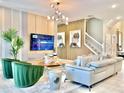 Bright and modern living room with a comfortable gray sofa, green chairs, and a stylish light fixture at 10012 Voyager Way, Orlando, FL 32821
