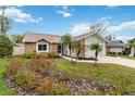 A quaint brick home, accented by a lush lawn, colorful flowers and mature palm trees at 1071 Sweet Tree Ct, Apopka, FL 32712