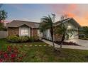 Charming brick home with a well-manicured lawn, landscape and mature palm trees at dusk at 1071 Sweet Tree Ct, Apopka, FL 32712