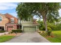 View of a green and orange two-story townhouse with a two-car garage and mature landscaping at 2015 Shalimar Loop, Sanford, FL 32773